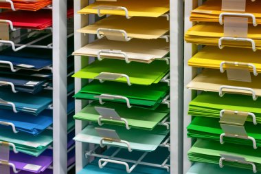 Rafta tasarım ve sanat için bir sürü renkli boş kağıt var. Dükkanda okul, kolej ve üniversite araçları olarak çok renkli çarşaf grubu. 