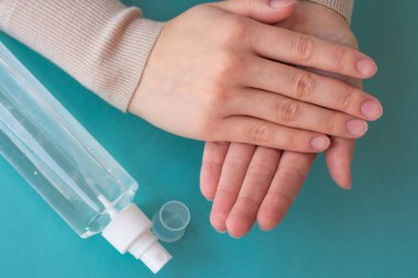 Ellerin antiseptik sıvıyla dolu sprey şişesi kullanışının üst görüntüsü. Sağlık, hijyen ve koronavirüsün yayılmasını önleme kavramı