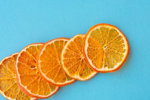 Row of dehydrated citrus fruits as tangerines on blue background. Slices of dried citrus fruits.