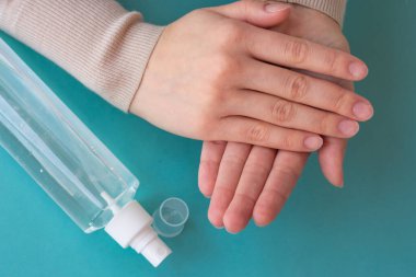 Ellerin antiseptik sıvıyla dolu sprey şişesi kullanışının üst görüntüsü. Sağlık, hijyen ve koronavirüsün yayılmasını önleme kavramı