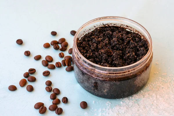 Round jar full of coffee scrub with roasted beans and sea salt as homemade facial and body exfoliation treatment. Homemade cosmetics for peeling and rejuvenation, anti-cellulite spa product
