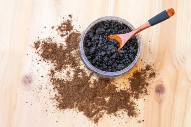 Ev yapımı yüz bakımı ve ahşap arka planda kaşıkla vücut fırçası olarak zeytin yağı ve tuzlu kahve fırçası dolu bir kase. Soymak ve gençleştirmek için ev yapımı kozmetik ürünler, anti-selülit spa ürünleri