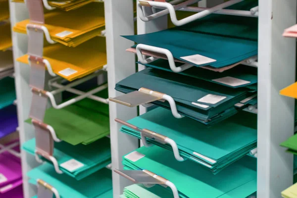 Rafta tasarım ve sanat için bir sürü renkli boş kağıt var. Dükkanda okul, kolej ve üniversite araçları olarak çok renkli çarşaf grubu. 