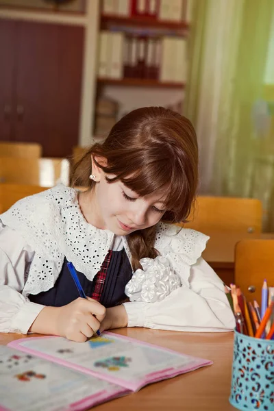 the girl is studying. The first lesson at the school desk, the task in the notebook.