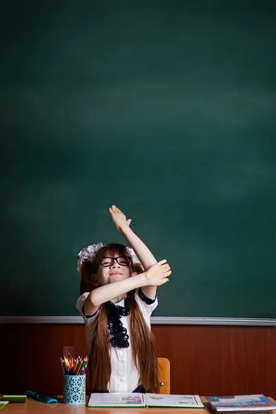 back to school. the girl at the desk draws her arm up.