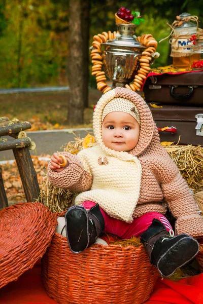 autumn portrait of a child in a rural yard, Russian customs, a samovar with bagels in nature in yellow foliage.