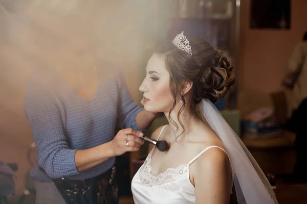 Make-up artist doing makeup to the bride on the wedding day. large portrait. contouring with a brush.