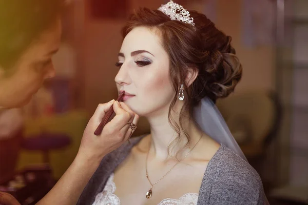 Make-up artist doing makeup to the bride on the wedding day. large portrait.