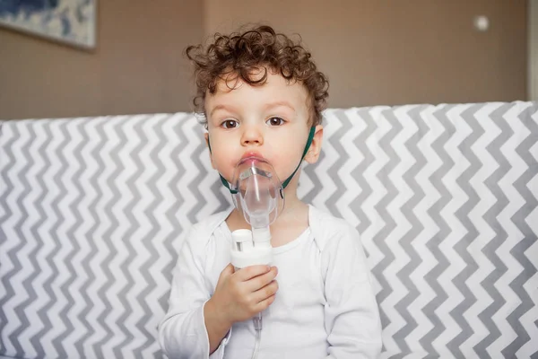 cough treatment by inhalation. baby with a nebulizer in his hands.