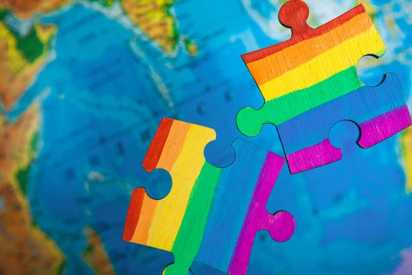 LGBT as a part of society - one puzzle with the coloring of the flag of sexual minorities on a blue globe background