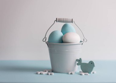 Yumurta serisi beyaz ve mavi boyalı, küçük bir kova, buctet. Bahar ve Paskalya tatili konsepti.