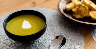 Ahşap masada siyah plaka yeşil brokoli & ıspanak sebze çorbası. Modern mutfak, yemek pişirme ve sağlıklı gıda konsepti. 