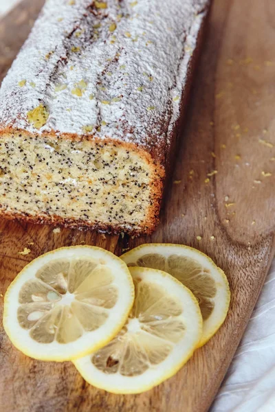 Cake with poppy seeds and lemon zest, sprinkled with powdered sugar. Cupcake with lemon on a wooden board. — Stock Photo, Image