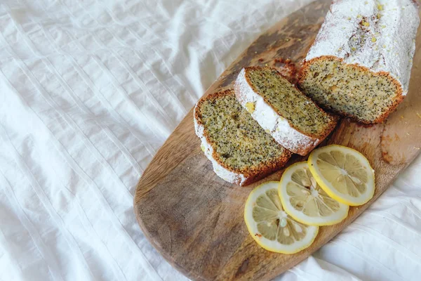 Tårta med vallmofrön och citron Zest, bevattnas med strös ocker. Cupcake med citron på en träskiva. — Stockfoto