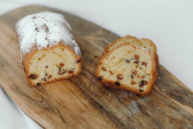 Kuru üzümlü kek, pudra şekeri ile tozlanmış. Ahşap bir tahta üzerinde kuru üzüm ile Cupcake.