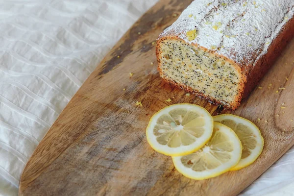 Tårta med vallmofrön och citron Zest, bevattnas med strös ocker. Cupcake med citron på en träskiva. — Stockfoto