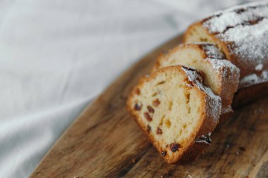 Kuru üzümlü kek, pudra şekeri ile tozlanmış. Ahşap bir tahta üzerinde kuru üzüm ile Cupcake.