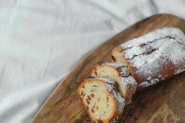 Kuru üzümlü kek, pudra şekeri ile tozlanmış. Ahşap bir tahta üzerinde kuru üzüm ile Cupcake.