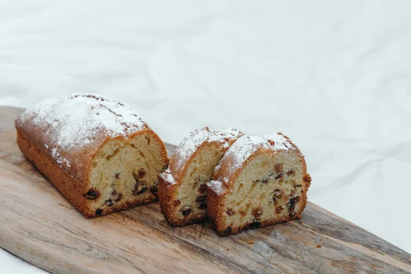 Bolo de ervilha, polvilhado com açúcar. Bolo com passas em uma tábua de madeira . — Fotografia de Stock