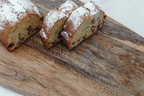 Kuru üzümlü kek, pudra şekeri ile tozlanmış. Ahşap bir tahta üzerinde kuru üzüm ile Cupcake.