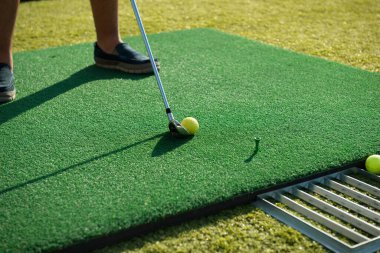 Bir adam golf oynuyor. Çimlerin üzerinde golf topları.