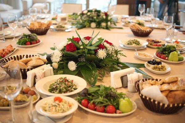 Yemekli şölen masası. Salatalar, taze sebzeler, ekmek, zeytin ve daha fazlası..