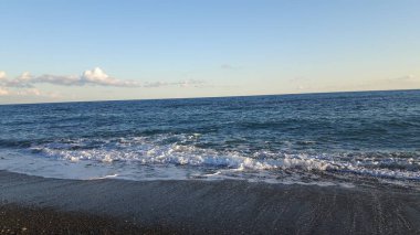 Güzel bir mavi denizi, küçük dalgalar ve sümer gün içinde gizli bir günbatımı horizzon üzerinde inanılmaz bir resim yazısı