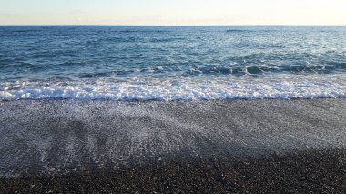 Güzel bir mavi denizi, küçük dalgalar ve sümer gün içinde gizli bir günbatımı horizzon üzerinde inanılmaz bir resim yazısı