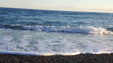 Güzel bir mavi denizi, küçük dalgalar ve sümer gün içinde gizli bir günbatımı horizzon üzerinde inanılmaz bir resim yazısı