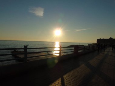 Genova, İtalya - 02/25/2019: bazı dalgalar ve Cenova şehir denize sıfır üzerinden günbatımı kış gün ve güneş tarafından renkli plaja yakın eski binalar için harika manzarası inanılmaz bir resim yazısı