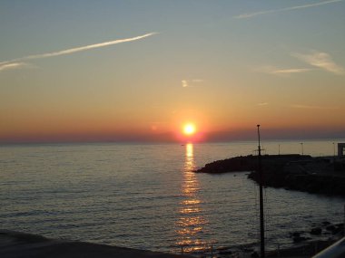 Genova, İtalya - 02/25/2019: bazı dalgalar ve Cenova şehir denize sıfır üzerinden günbatımı kış gün ve güneş tarafından renkli plaja yakın eski binalar için harika manzarası inanılmaz bir resim yazısı