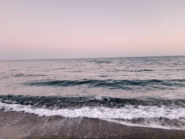 Genova, İtalya - 02/25/2019: bazı dalgalar ve Cenova şehir denize sıfır üzerinden günbatımı kış gün ve güneş tarafından renkli plaja yakın eski binalar için harika manzarası inanılmaz bir resim yazısı