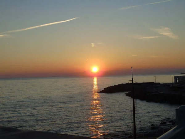 Genova, İtalya - 02/25/2019: bazı dalgalar ve Cenova şehir denize sıfır üzerinden günbatımı kış gün ve güneş tarafından renkli plaja yakın eski binalar için harika manzarası inanılmaz bir resim yazısı