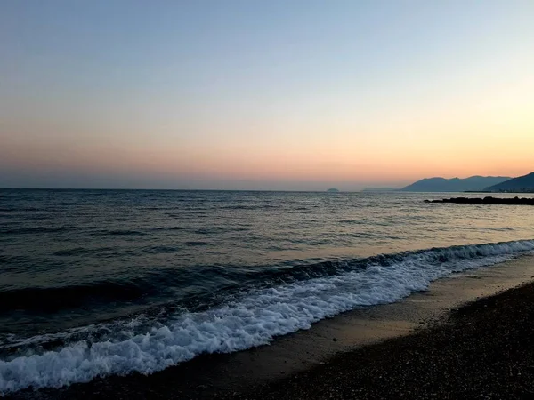 Genova, İtalya - 02/25/2019: bazı dalgalar ve Cenova şehir denize sıfır üzerinden günbatımı kış gün ve güneş tarafından renkli plaja yakın eski binalar için harika manzarası inanılmaz bir resim yazısı