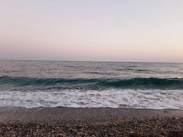 Genova, İtalya - 02/25/2019: bazı dalgalar ve Cenova şehir denize sıfır üzerinden günbatımı kış gün ve güneş tarafından renkli plaja yakın eski binalar için harika manzarası inanılmaz bir resim yazısı