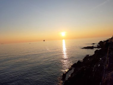 Küçük dalgalar ve kış günlerinde deniz ve bazı renkli bulutlar üzerinde inanılmaz bir yansıması ile güzel gün batımı harika bir resim yazısı