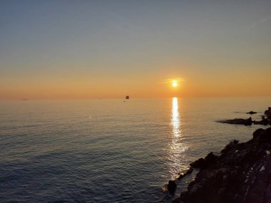 Küçük dalgalar ve kış günlerinde deniz ve bazı renkli bulutlar üzerinde inanılmaz bir yansıması ile güzel gün batımı harika bir resim yazısı