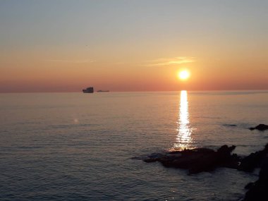 Küçük dalgalar ve kış günlerinde deniz ve bazı renkli bulutlar üzerinde inanılmaz bir yansıması ile güzel gün batımı harika bir resim yazısı