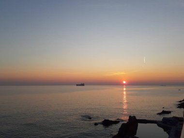 Küçük dalgalar ve kış günlerinde deniz ve bazı renkli bulutlar üzerinde inanılmaz bir yansıması ile güzel gün batımı harika bir resim yazısı