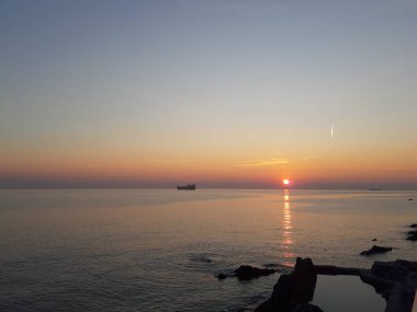 Küçük dalgalar ve kış günlerinde deniz ve bazı renkli bulutlar üzerinde inanılmaz bir yansıması ile güzel gün batımı harika bir resim yazısı