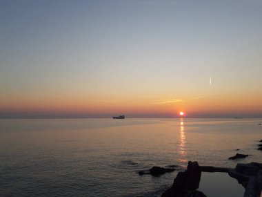 Küçük dalgalar ve kış günlerinde deniz ve bazı renkli bulutlar üzerinde inanılmaz bir yansıması ile güzel gün batımı harika bir resim yazısı