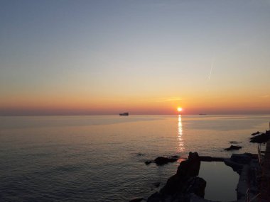 Küçük dalgalar ve kış günlerinde deniz ve bazı renkli bulutlar üzerinde inanılmaz bir yansıması ile güzel gün batımı harika bir resim yazısı