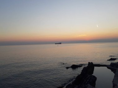 Küçük dalgalar ve kış günlerinde deniz ve bazı renkli bulutlar üzerinde inanılmaz bir yansıması ile güzel gün batımı harika bir resim yazısı