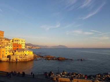 Genova, İtalya - 15.04.2019: Cenova'nın küçük bir deniz bölgesi olan Boccadasse, altın saat boyunca bazı insanların keyfini çıkarıyor