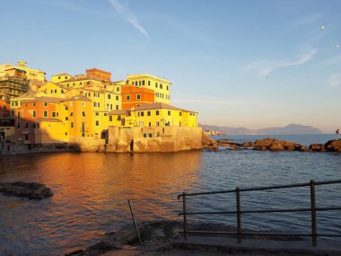 Genova, İtalya - 15.04.2019: Cenova'nın küçük bir deniz bölgesi olan Boccadasse, altın saat boyunca bazı insanların keyfini çıkarıyor