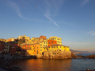 Genova, İtalya - 15.04.2019: Cenova'nın küçük bir deniz bölgesi olan Boccadasse, altın saat boyunca bazı insanların keyfini çıkarıyor