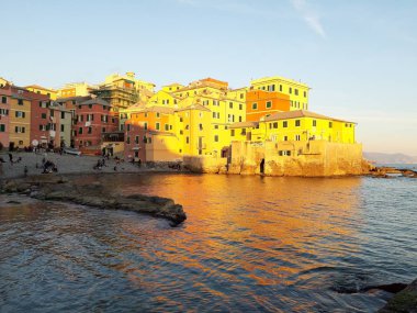 Genova, İtalya - 15.04.2019: Cenova'nın küçük bir deniz bölgesi olan Boccadasse, altın saat boyunca bazı insanların keyfini çıkarıyor