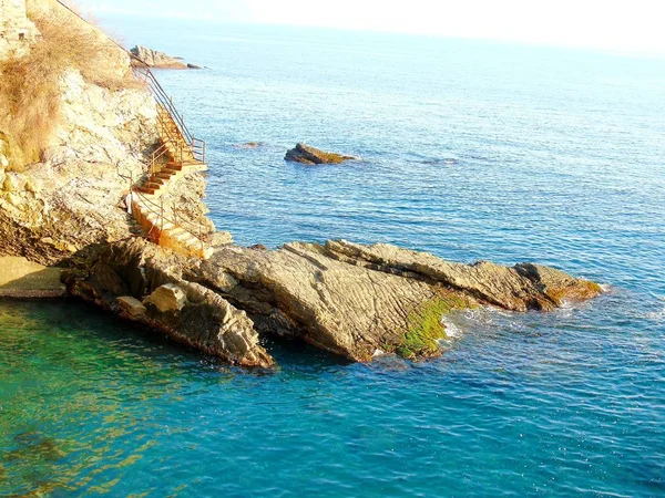 ジェノバ イタリア 2019 美しい赤と青の空とジェノバの海の上に春の日の夕日の素晴らしいキャプション 背景にいくつかの素晴らしい雲と海の上の古い岩 — ストック写真