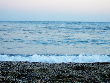 Genova, İtalya - 15.03.2019: Güzel kırmızı ve mavi gökyüzü, arka planda bazı şaşırtıcı bulutlar ve deniz üzerinde eski kayalar ile Genova denizi üzerinde bahar günlerinde gün batımı inanılmaz bir başlık.