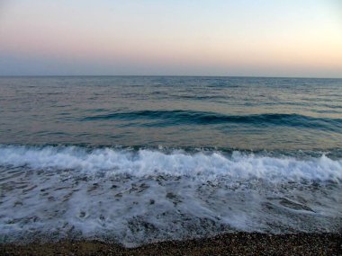 Genova, İtalya - 15.03.2019: Güzel kırmızı ve mavi gökyüzü, arka planda bazı şaşırtıcı bulutlar ve deniz üzerinde eski kayalar ile Genova denizi üzerinde bahar günlerinde gün batımı inanılmaz bir başlık.